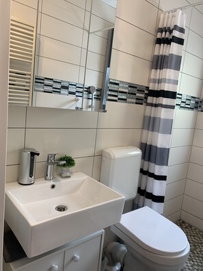 A bathroom with a white sink, a toilet, a shower curtain, and a mirror. - Apartment La Lucia (Schwaebisch Gmuend)