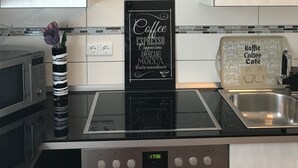 Una cocina moderna con horno integrado, estación de café y televisor de pantalla plana sobre la encimera.