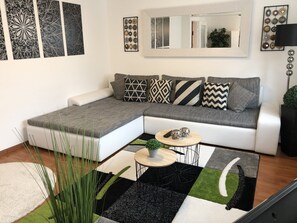 A modern living room with a sectional sofa, a coffee table, and decorative wall art. - Apartment La Lucia (Schwaebisch Gmuend)