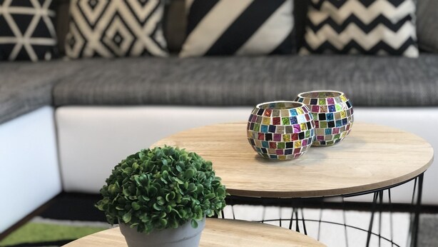 Una mesa redonda de madera con una planta en maceta y dos jarrones de mosaico.