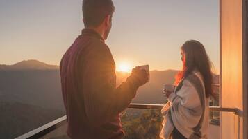 Una pareja parada junto a una ventana con vistas a un paisaje escénico al atardecer.
