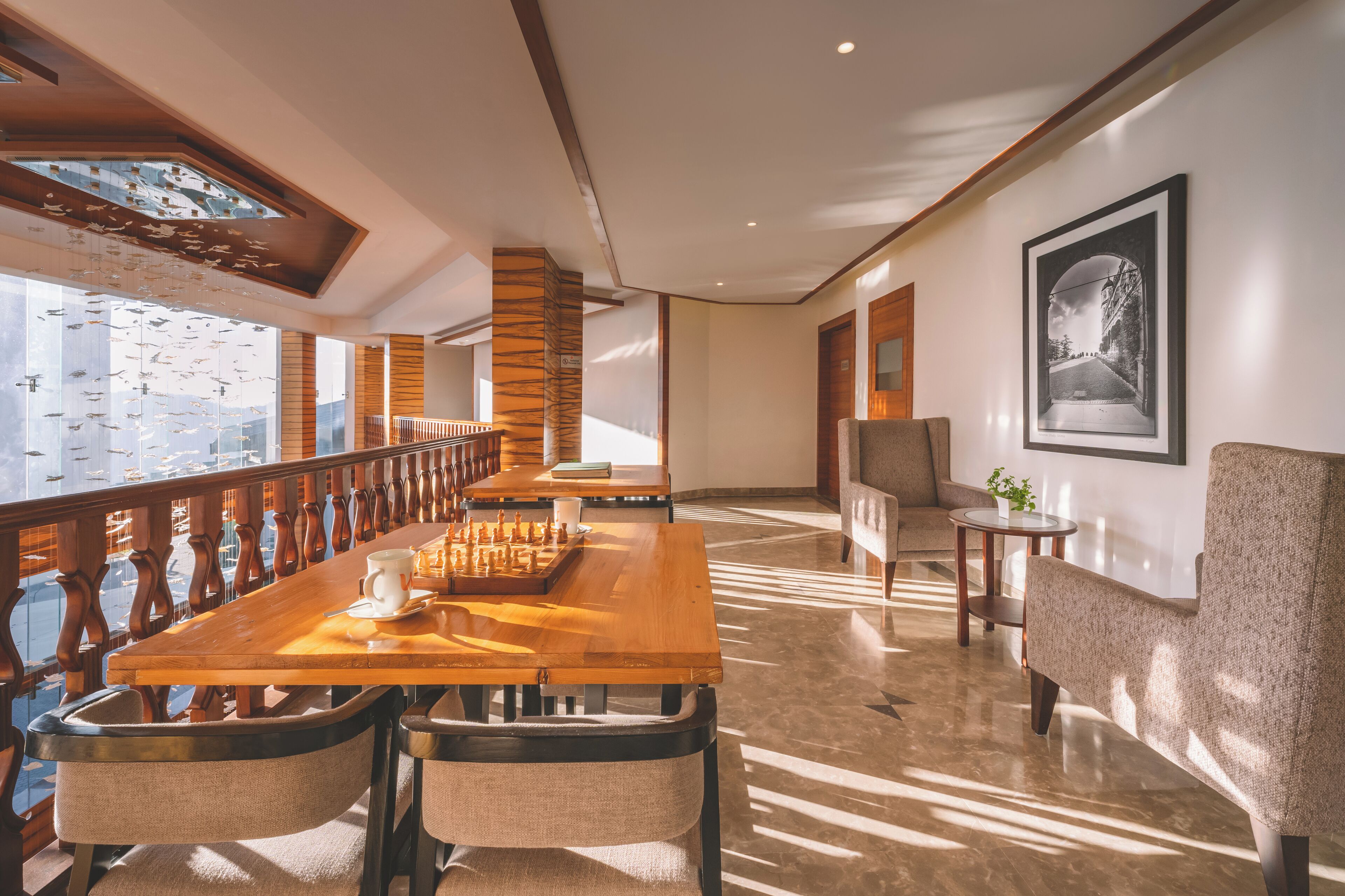 Un comedor amplio con una larga mesa de madera, sillas acolchadas y vistas de la ciudad a través de grandes ventanales.