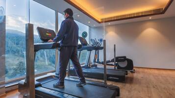 Een fitnessruimte met loopbanden, een hometrainer en een roeimachine.