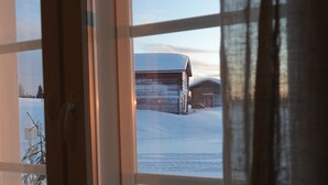 Une fenêtre donnant sur un paysage enneigé et un bâtiment en bois.