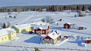 Un paysage rural enneigé, avec plusieurs maisons et une zone délimitée par une clôture.