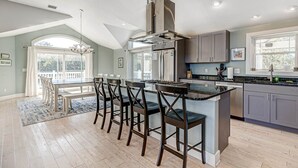 Een moderne keuken met een centraal eiland, barstoelen en een eethoek met uitzicht.