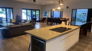 A modern kitchen with a central island, dining area with chairs, and a sofa.