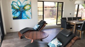 A modern living room with two black leather sofas, a round wooden coffee table, and a large abstract painting on the wall.