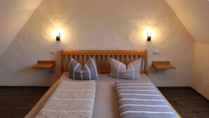 Een slaapkamer met twee eenpersoonsbedden, houten hoofdborden en nachtkastjes met wandlampen.