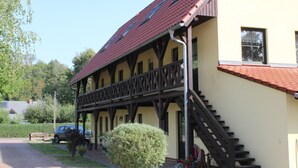 Een gebouw met een rode pannendak, houten balkonhekken en een trap naar de ingang.