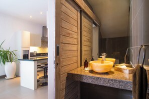 Features a large oval-shaped sink, glass-enclosed shower, and large mirror.