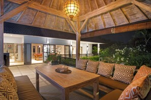 Cozy space with a high ceiling, central table, and lush greenery, surrounded by artwork and a door to another room.