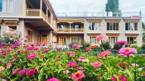 Ein traditionelles Gebäude mit Balkonen und einem Garten voller farbenprächtiger Blumen.