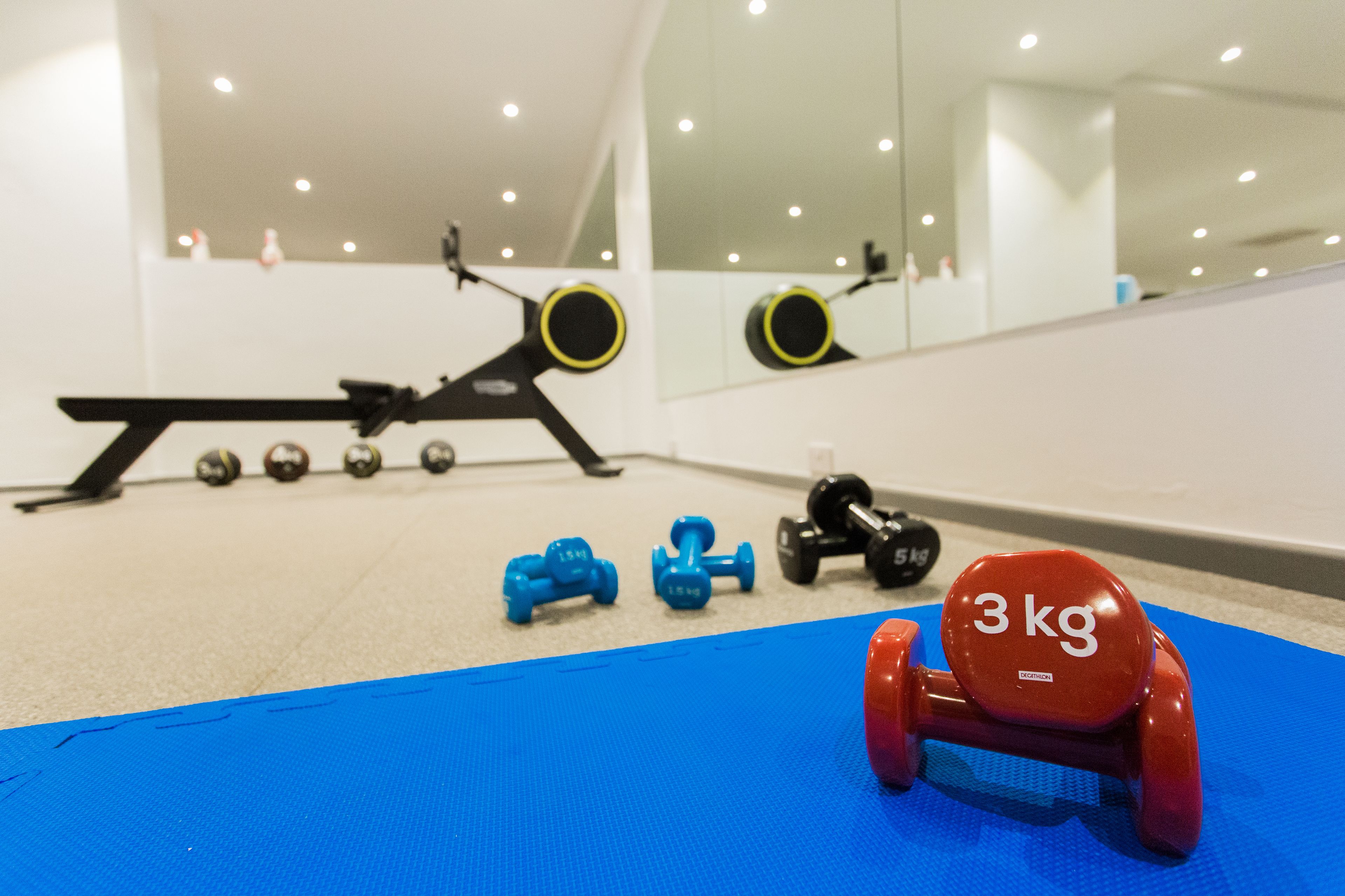 A gym with exercise equipment, including dumbbells and a bench.