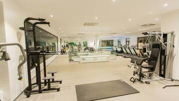 A gym with treadmills, weight machines, and a mirrored wall.