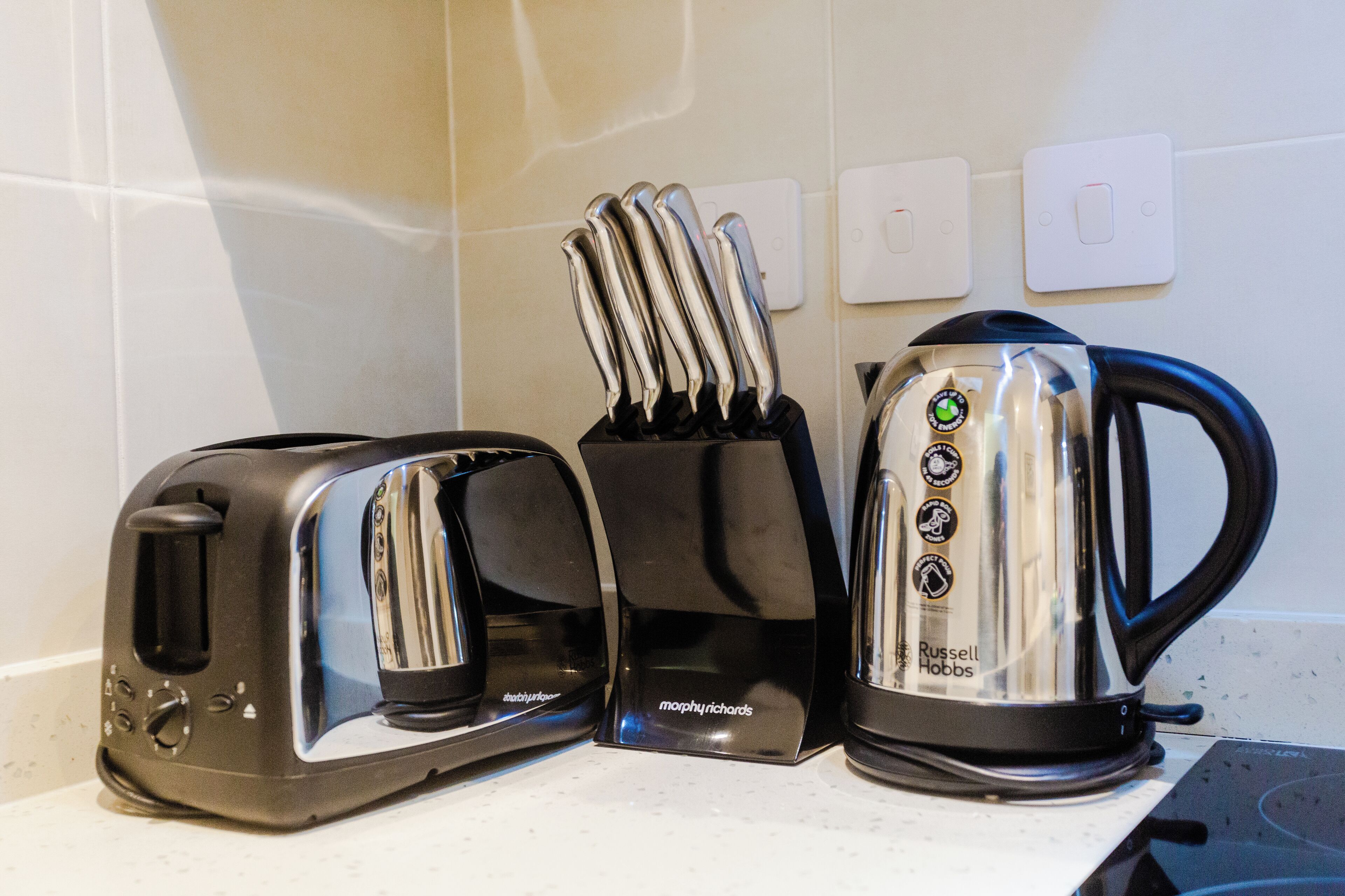 A kitchen counter with a toaster, a knife block, and a kettle.