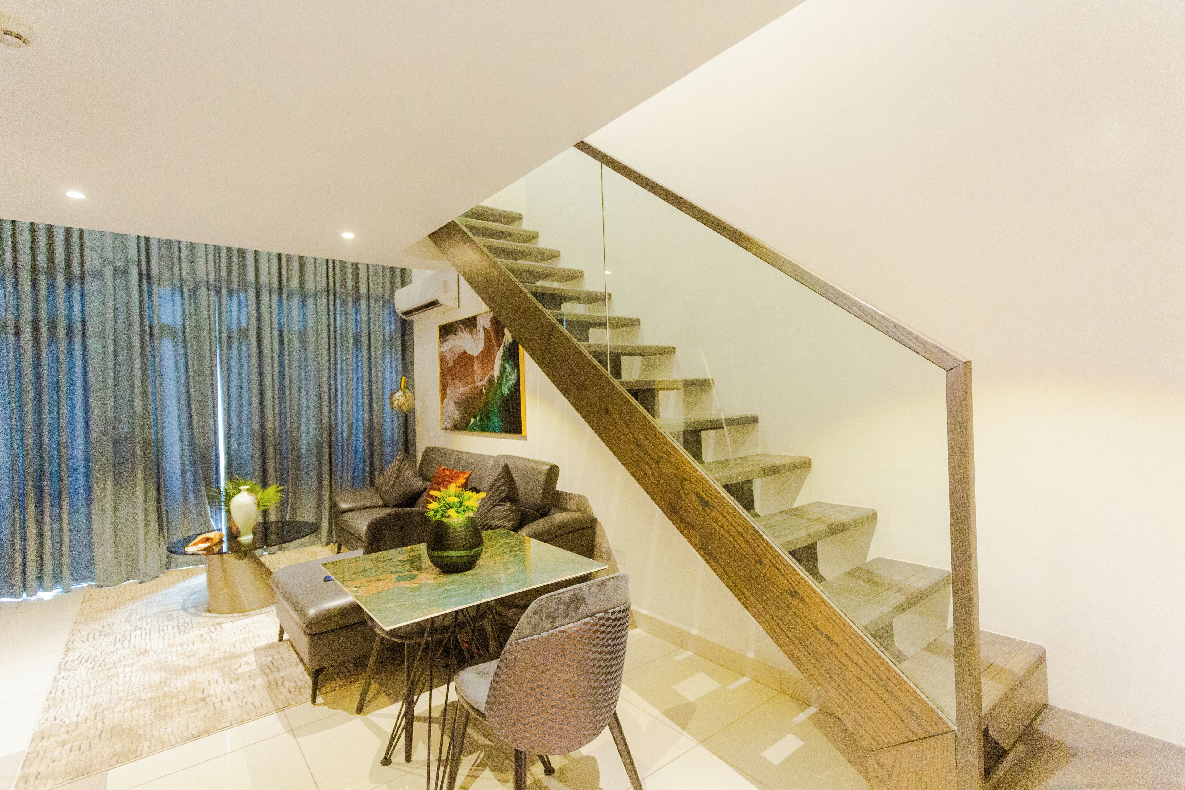 A modern living room with a glass staircase, a dining table, and a sofa.