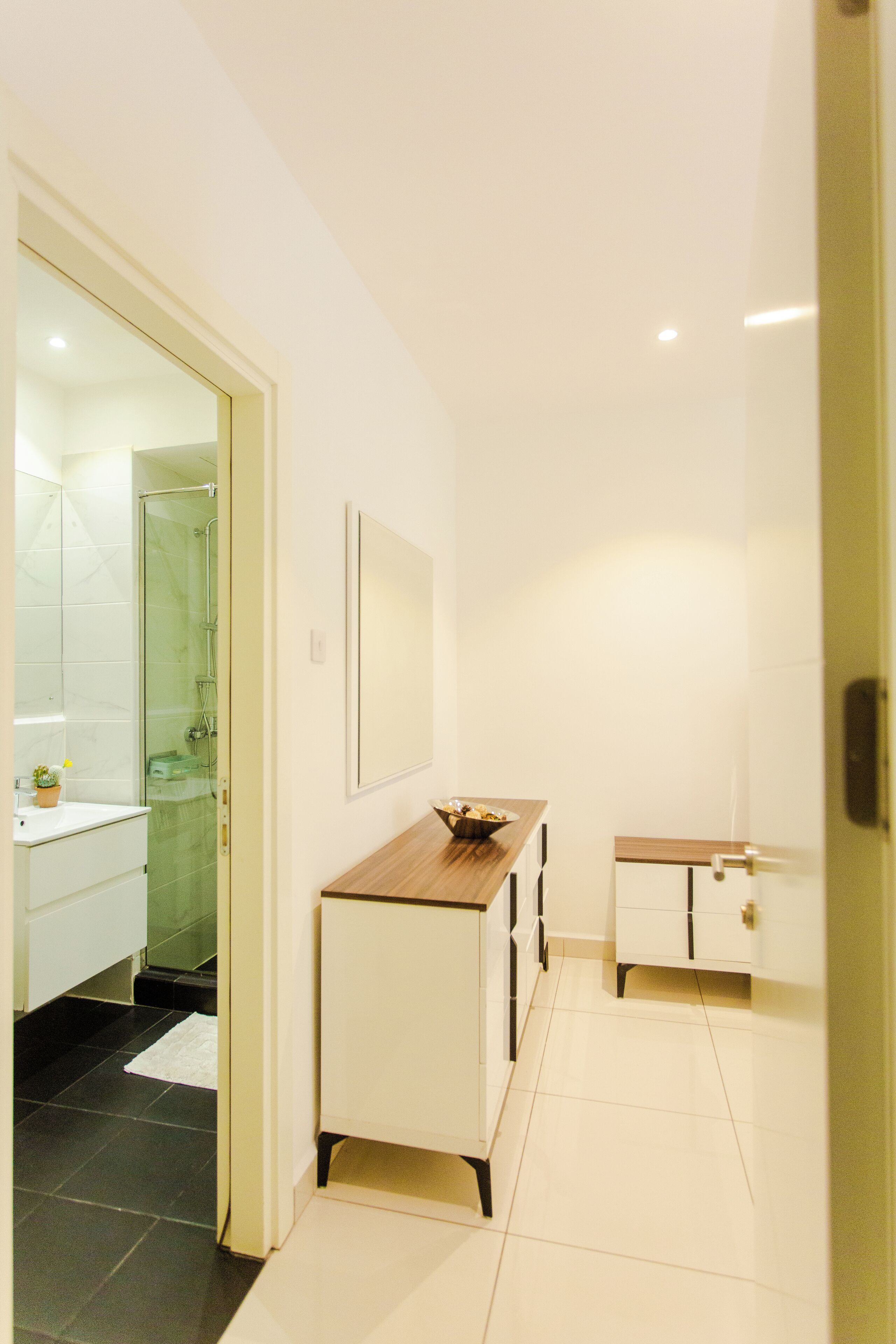 Un baño moderno con ducha de vidrio, muebles blancos y tocador de madera.