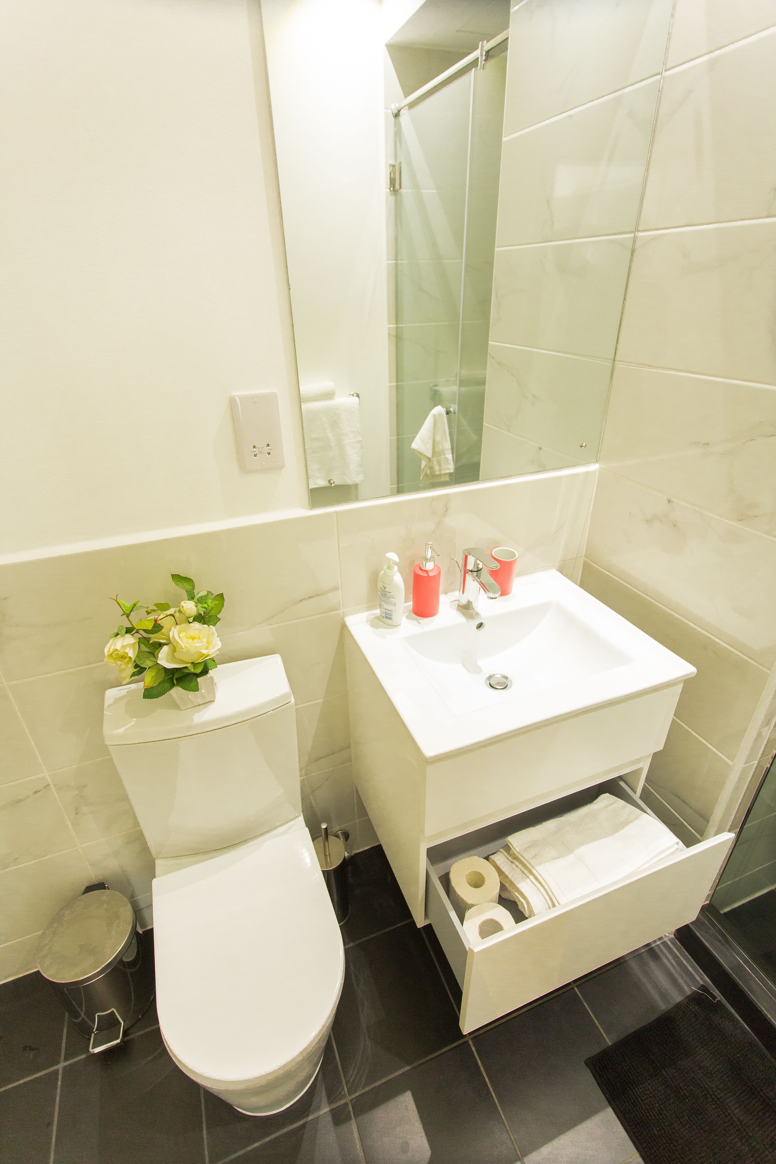 A bathroom with a toilet, sink, and a small trash bin.