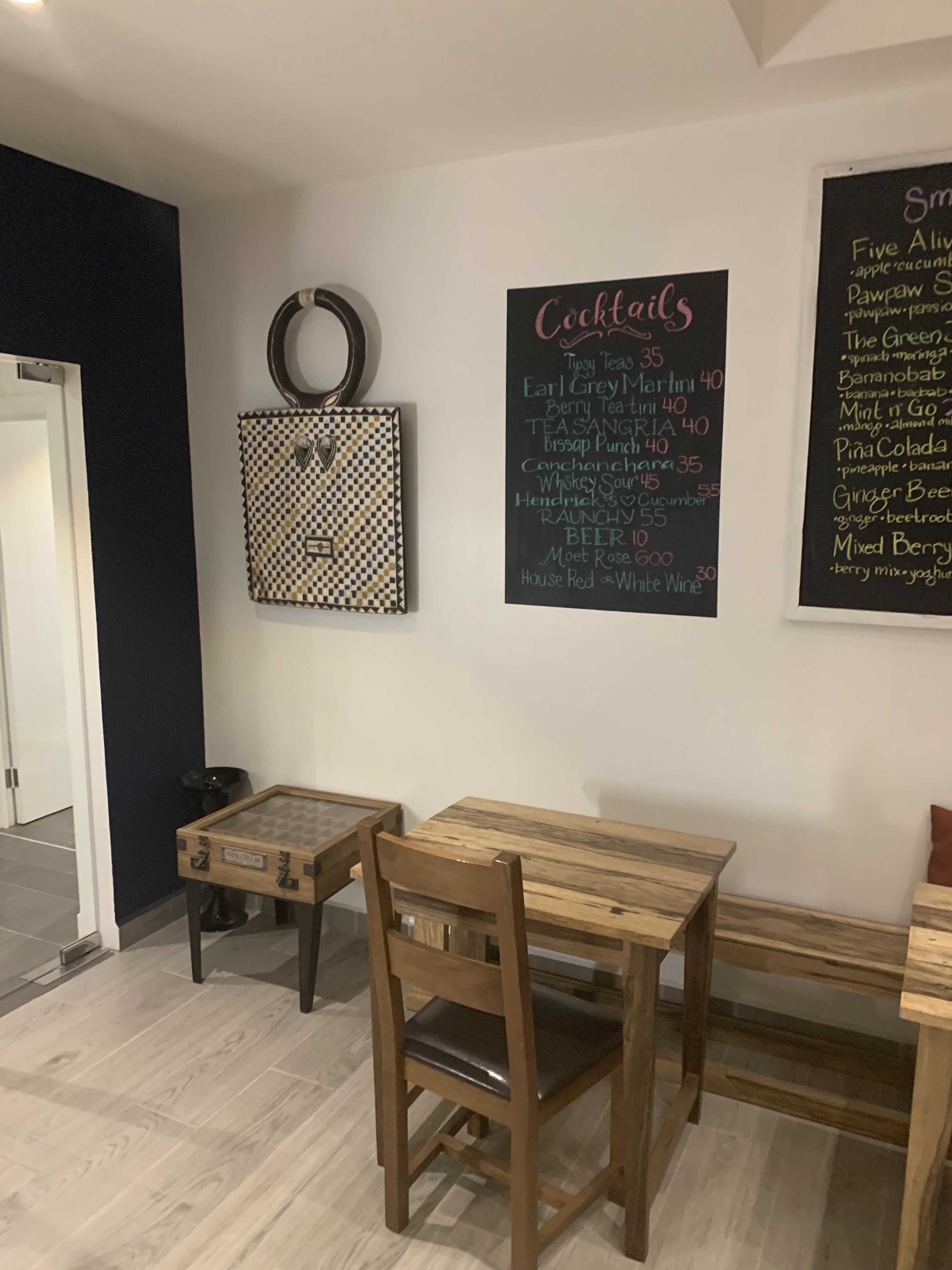A dining area with a wooden table and chairs, a chalkboard menu, and a decorative wall piece.