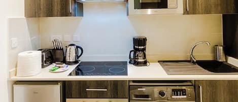Una cocina compacta equipada con microondas, cafetera, tostadora y lavadora.