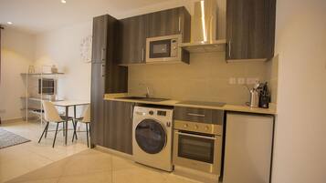 A modern kitchen with a built-in washer and dryer, a microwave, and a refrigerator.