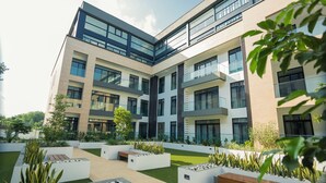 Een modern meerlaags gebouw met een binnentuin met plantenbakken, banken en een gazon.