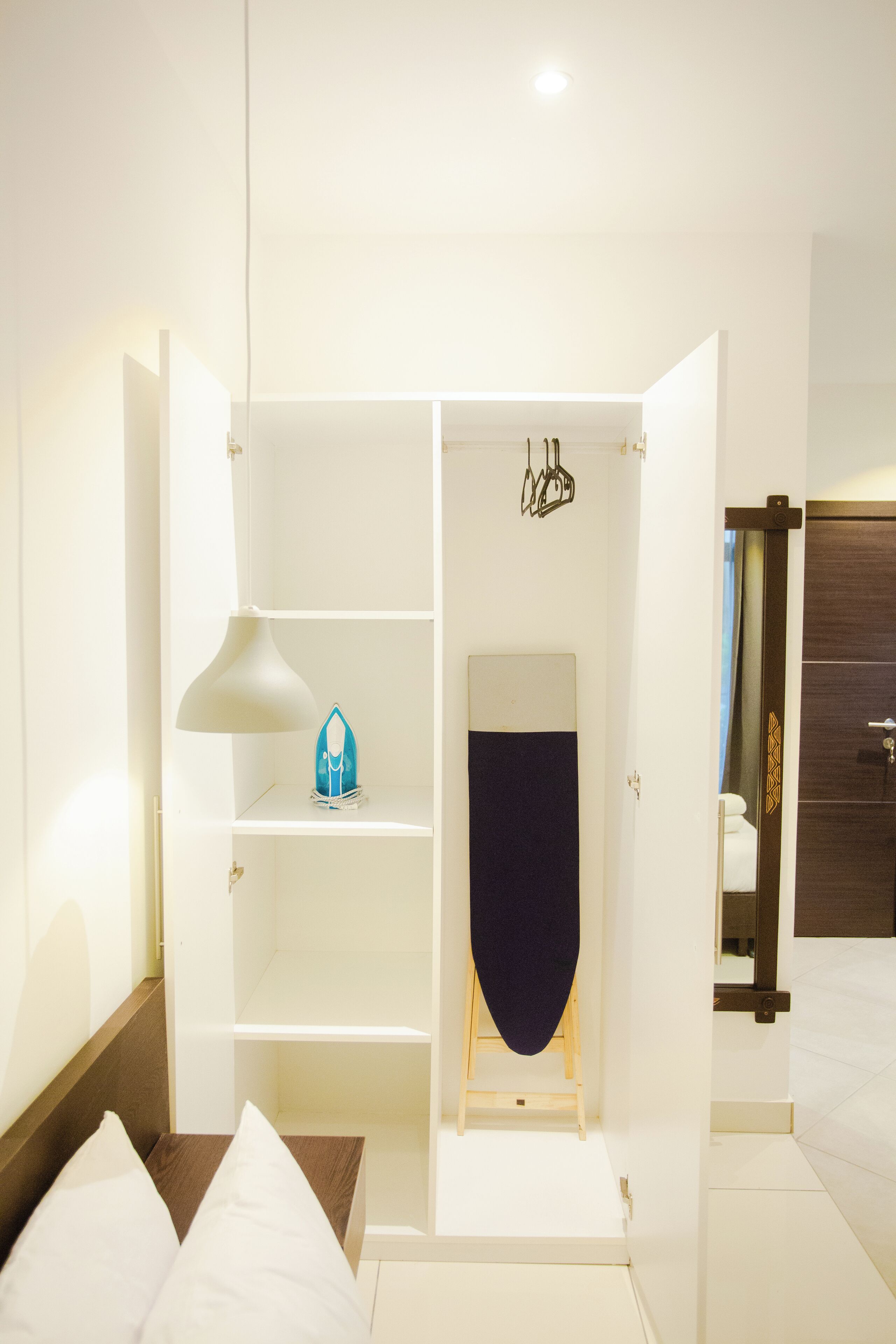 Une chambre d’hôtel avec un lit, une armoire, un bureau et un miroir.
