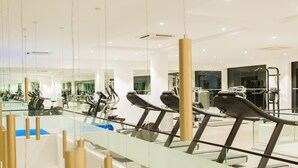Een moderne sportschool met loopbanden, fitnessapparatuur en een glazen wand die het interieur weerspiegelt.