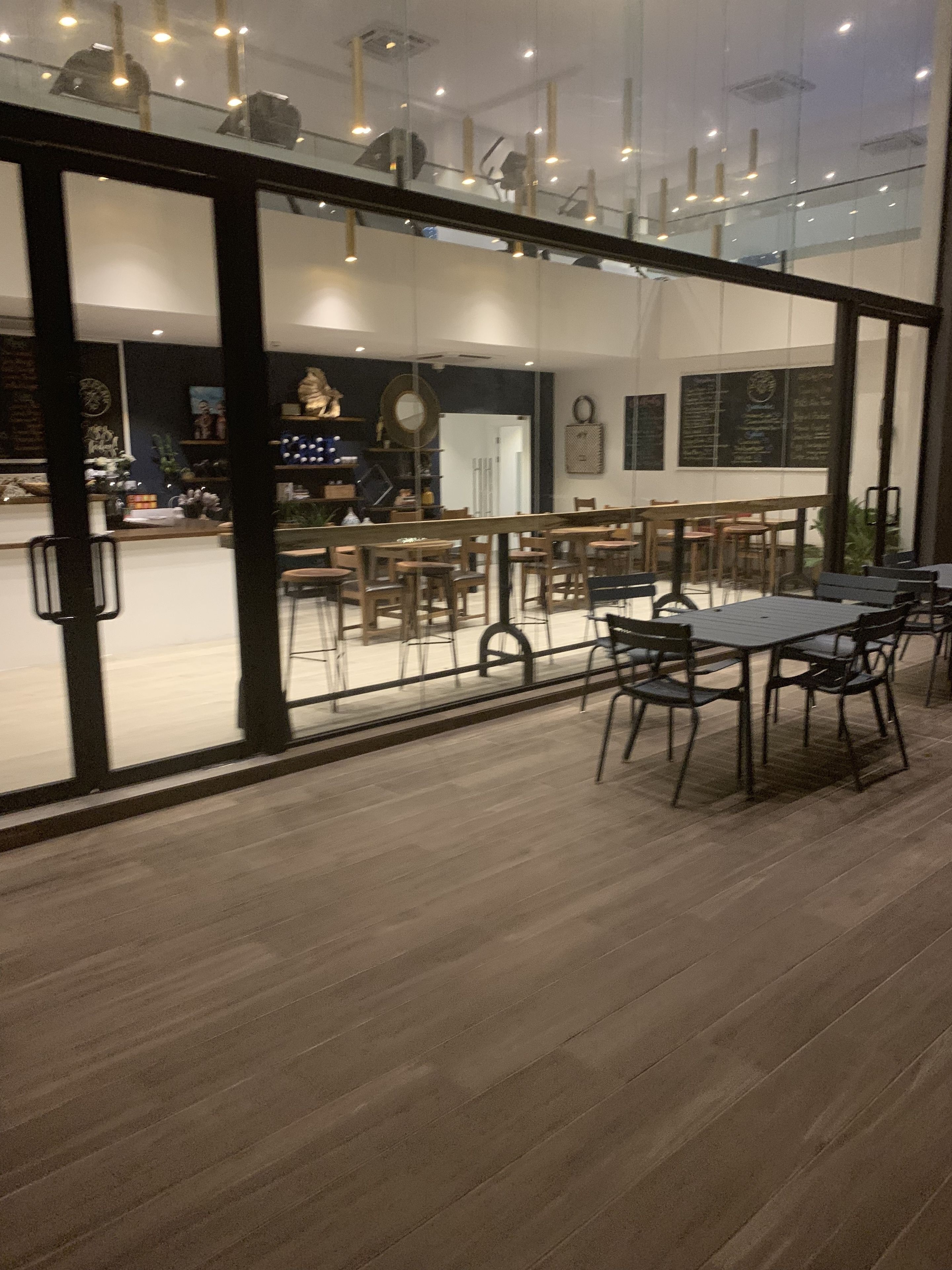 A modern interior with wooden flooring, glass partitions, and multiple tables and chairs.