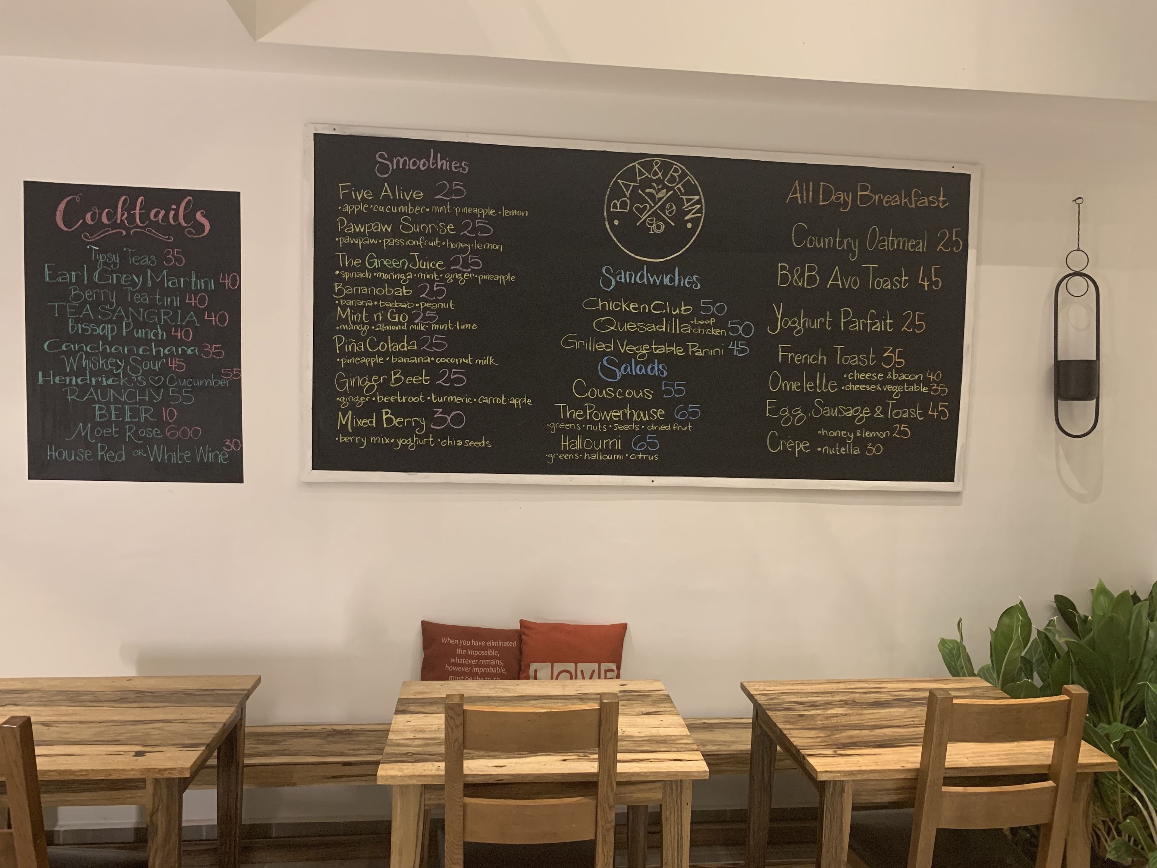 Un restaurant amb un menú escrit en pissarra que inclou còctels, batuts, entrepans, amanides i plats per esmorzar.