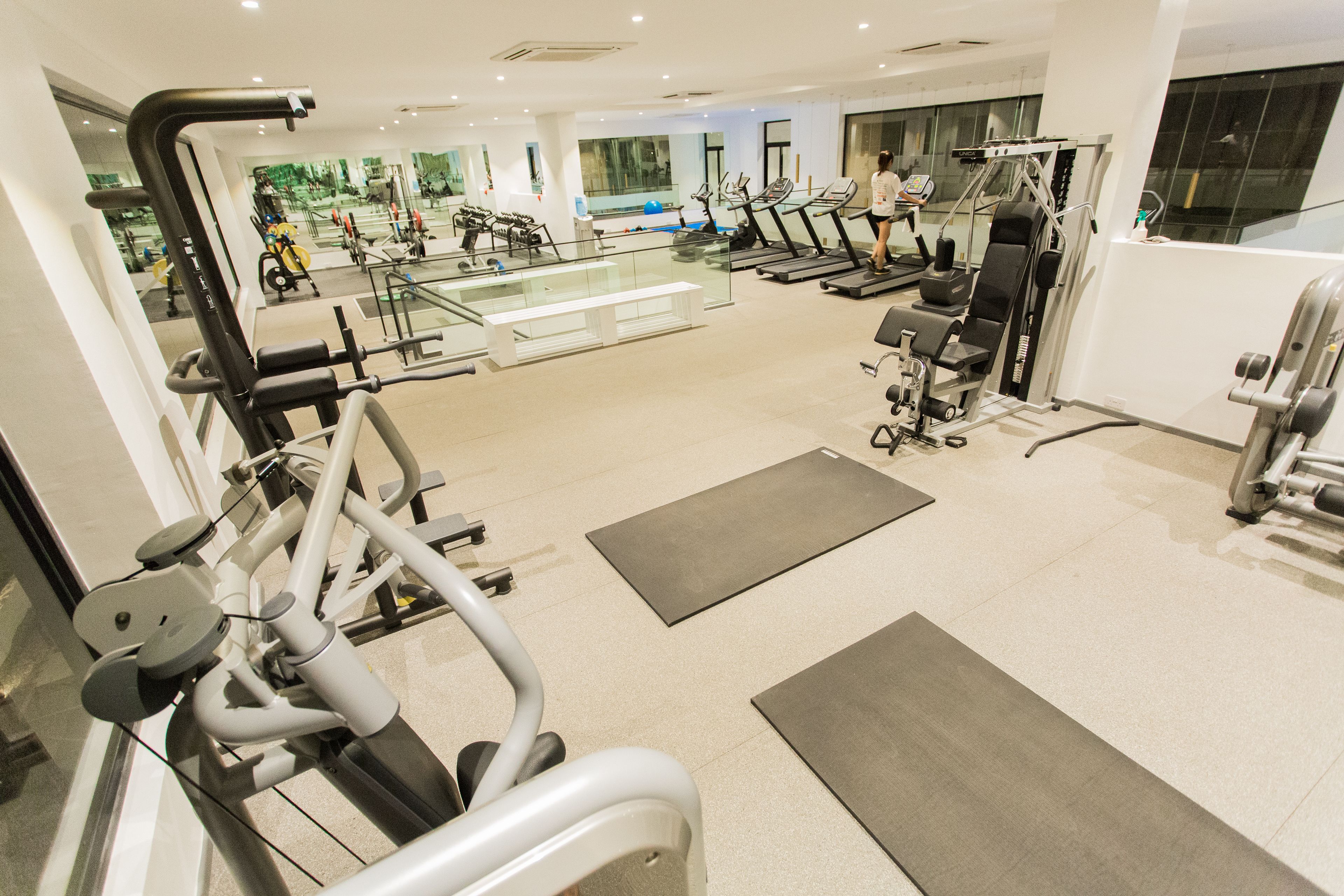 Een moderne sportschool met diverse trainingsapparaten, een glazen wand met uitzicht op de stad, en een ruime indeling.