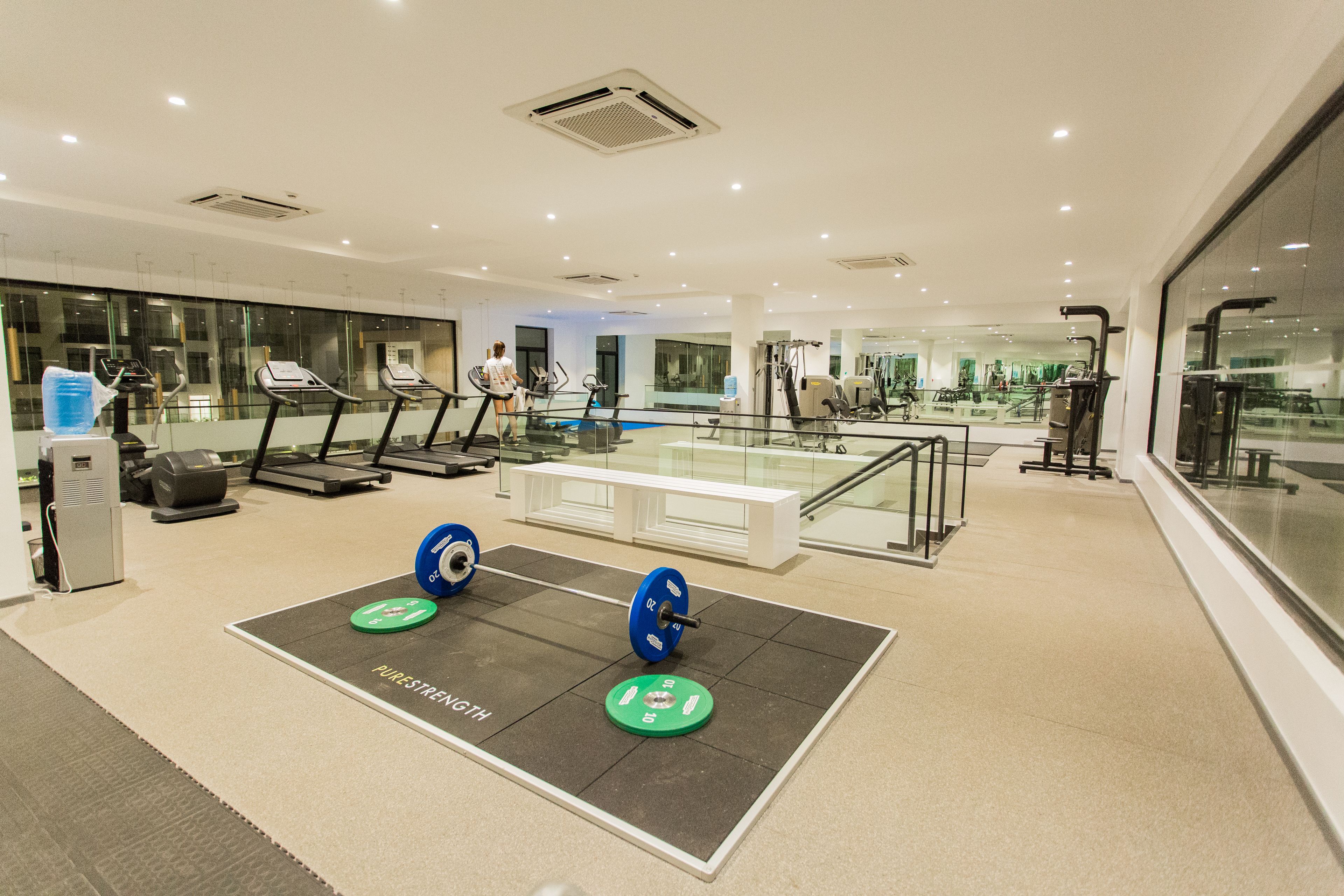 Een moderne sportschool met loopbanden, gewichthefapparatuur en een spiegelwand.