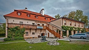 Un bâtiment traditionnel avec un toit recouvert de tuiles rouges, un balcon en bois et un escalier en pierre menant à l’entrée.