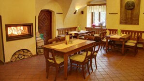 Un coin repas chaleureux avec des tables et des chaises en bois, une cheminée et une plaque décorative au mur.