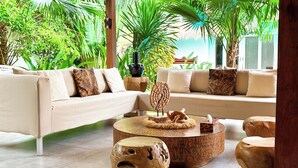 A modern living room with a beige sofa, round wooden coffee table, and a large potted plant.