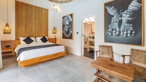 A modern bedroom with a wooden bed, a woven ceiling light, and two framed artworks.