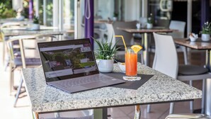 A laptop on a table with a drink and a plant. - Smart-HOTEL MINUSIO, a Swiss Quality Hotel (Minusio)