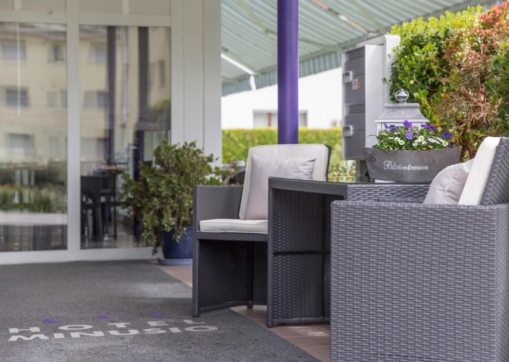 Ein Hotel Eingangsbereich mit einer Korbschaukel-Lounge, einer Tür mit einem Schild und einem Blumentopf mit Blumen.