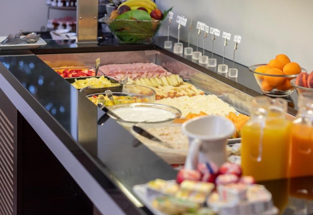 Buffet com diversos tipos de comida e uma cesta de frutas.