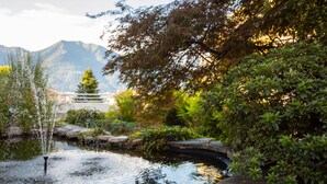 A tranquil garden with a pond, surrounded by lush greenery and a mountain backdrop. - Smart-HOTEL MINUSIO, a Swiss Quality Hotel (Minusio)