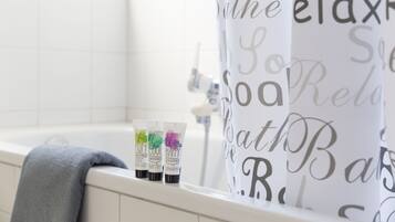 Un baño con bañera, una cortina de ducha con el texto 'Bath Relax' y tres botellas de productos de baño en el borde de la bañera.