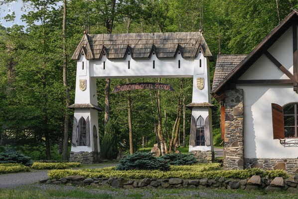 En traditionel bygning med en stenfassade og et trætag, omgivet af frodigt grønt og en stentrappe.