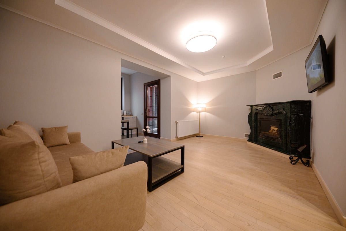 Una sala de estar con un sofá, una mesa de centro, una chimenea y un televisor montado en la pared.