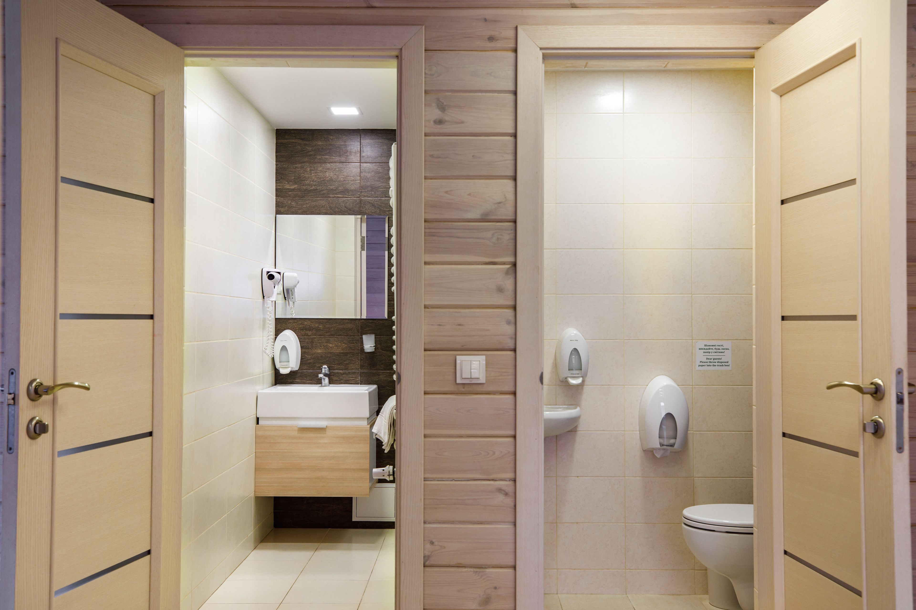 Un baño con pared de paneles de madera, un lavamanos, un espejo y un inodoro.