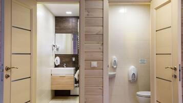 A bathroom with a wooden panel wall, a sink, a mirror, and a toilet.