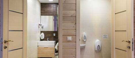 Un baño con pared de paneles de madera, un lavamanos, un espejo y un inodoro.