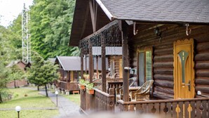 A row of log cabins with wooden balconies, outdoor seating, and potted plants. - Voevodyno Resort (Turia Pasika)