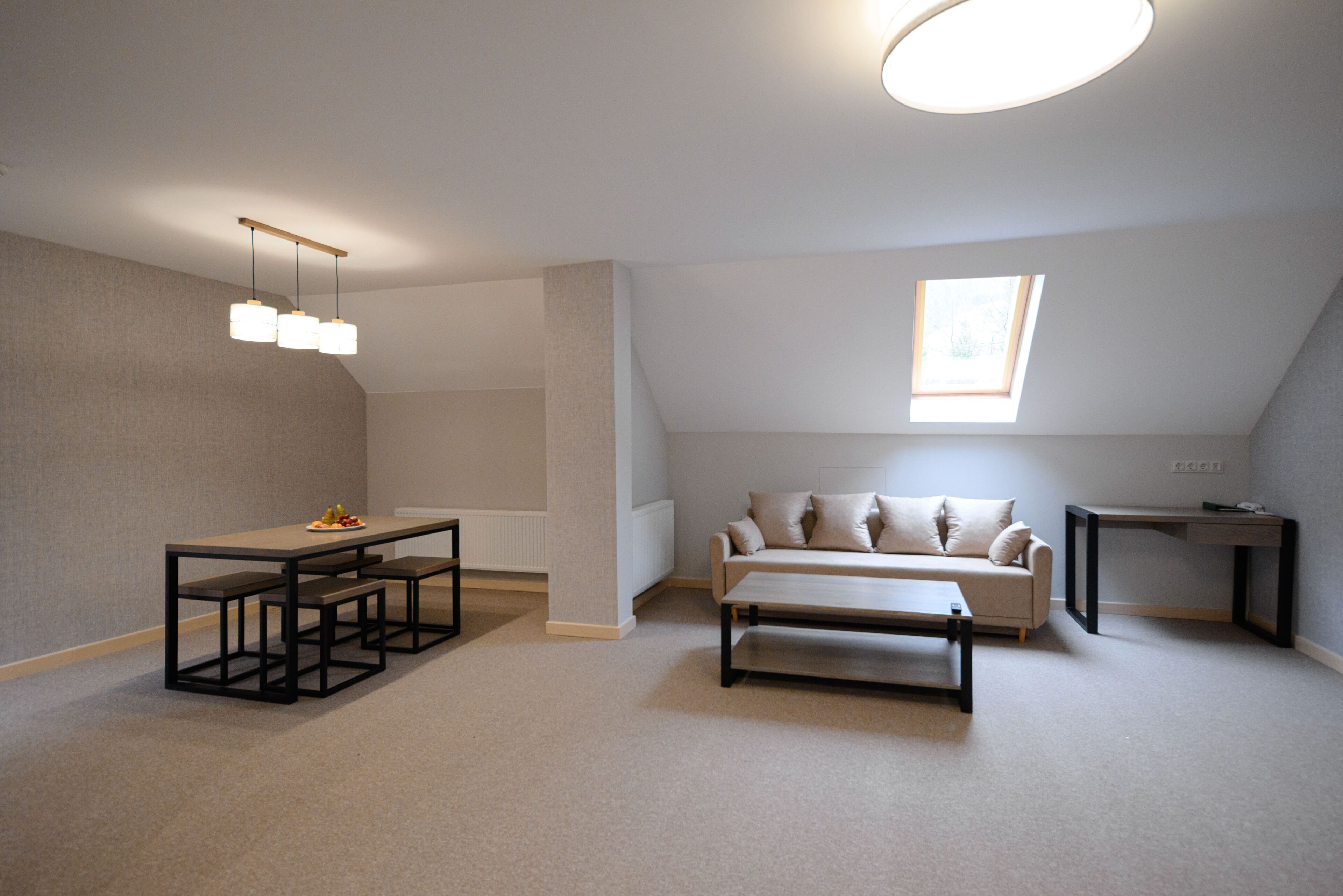 Un loft moderno y bien iluminado con un comedor, un sofá y un escritorio pequeño.