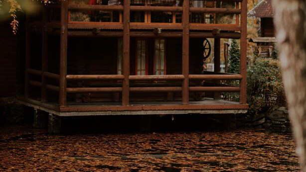 A wooden cabin with a balcony, surrounded by autumn foliage. - Voevodyno Resort (Turia Pasika)